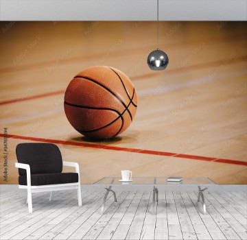 Picture of Classic Basketball on Wooden Court Floor Close Up with Blurred Arena in Background Orange Ball on a Hardwood Basketball Court